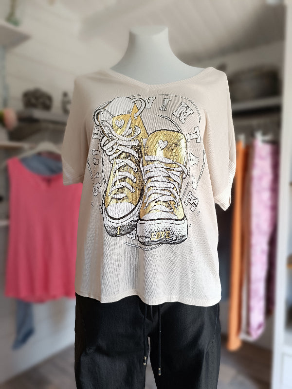 Leicht transparentes Sommer Shirt. Zeitlose Farbe Beige. Sneaker in Metallic Gold zieren die Vorderseite. V-Ausschnitt und kurze Arme mit Strickbund